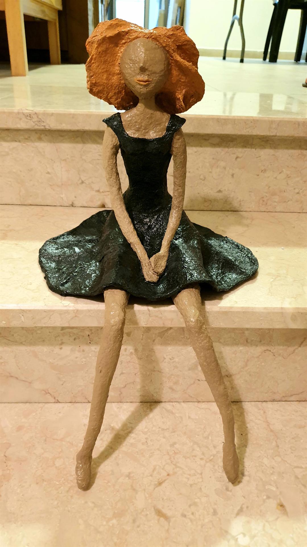 פסל מעיסת נייר של נערה יושבת על מדרגות שפיסלה אורית