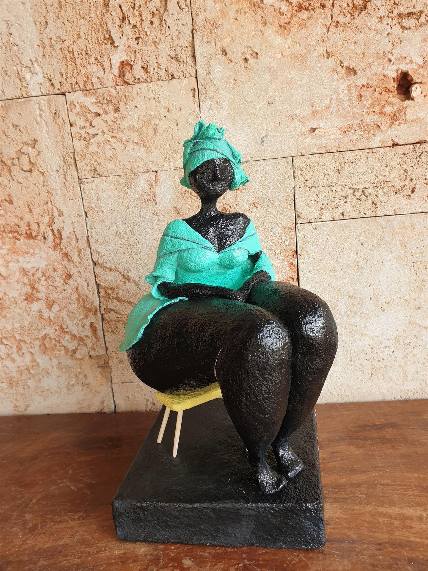 אשה בשמלה ומטפחת בטורקיז יושבת על ספסל קטן.